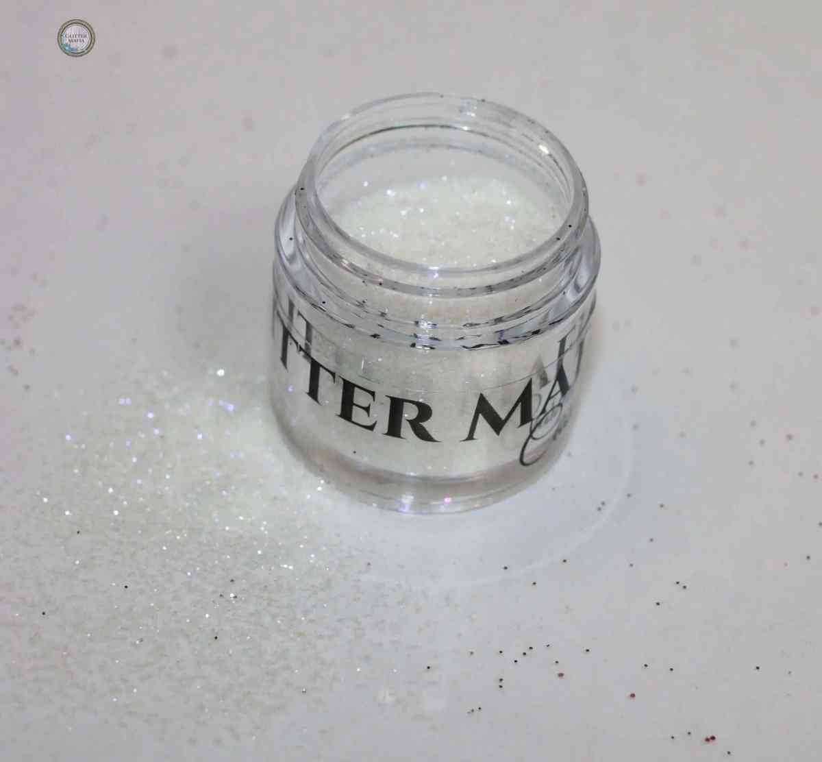 Glitter Mafia Faking It Loose Glitter in a clear jar with sparkly white loose glitter spilled around