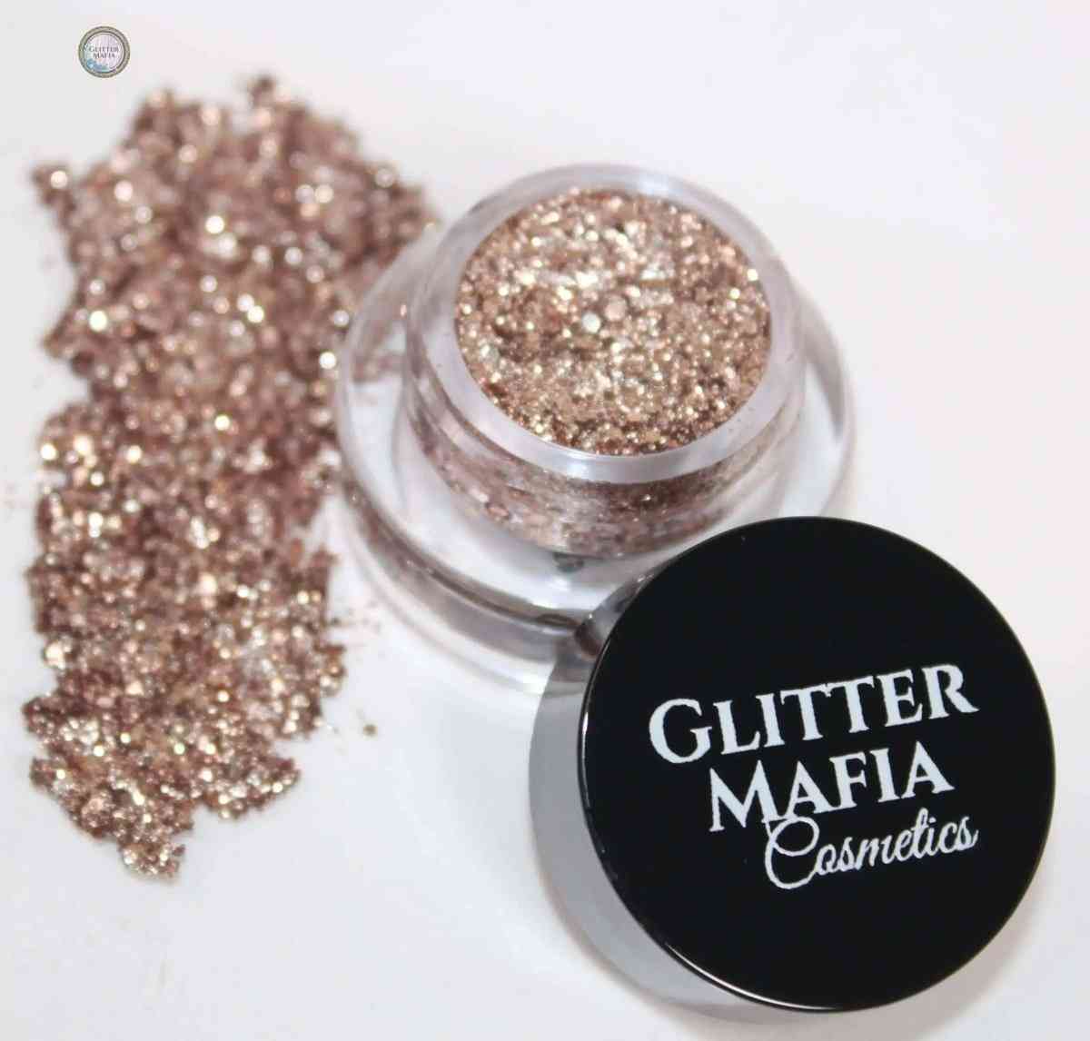 Glitter Mafia Gold Drip Pressed Glitter in small container with spilled gold shimmer on white surface