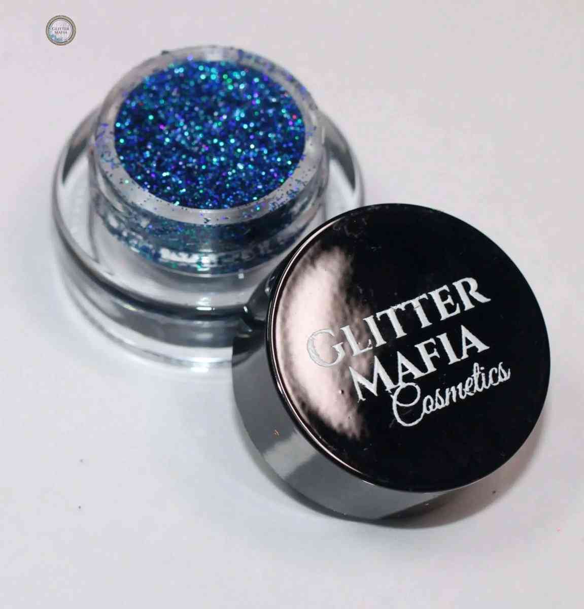 Glitter Mafia Peacock Pressed Glitter in a small clear container with black lid for vibrant makeup looks