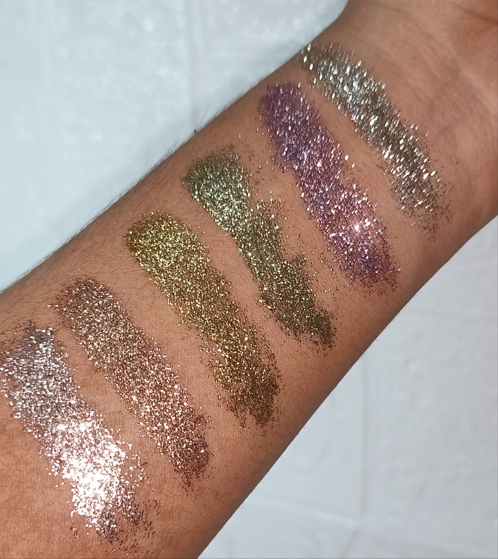 Swatches of Glitter Mafia 6-in-1 Pressed Glitter Eyeshadow in bridal and festive shades on arm