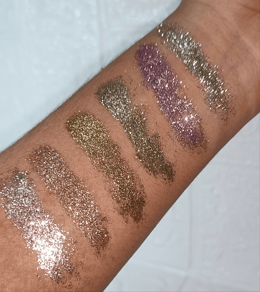 Swatches of Glitter Mafia 6-in-1 Pressed Glitter Eyeshadow in bridal and festive shades on arm