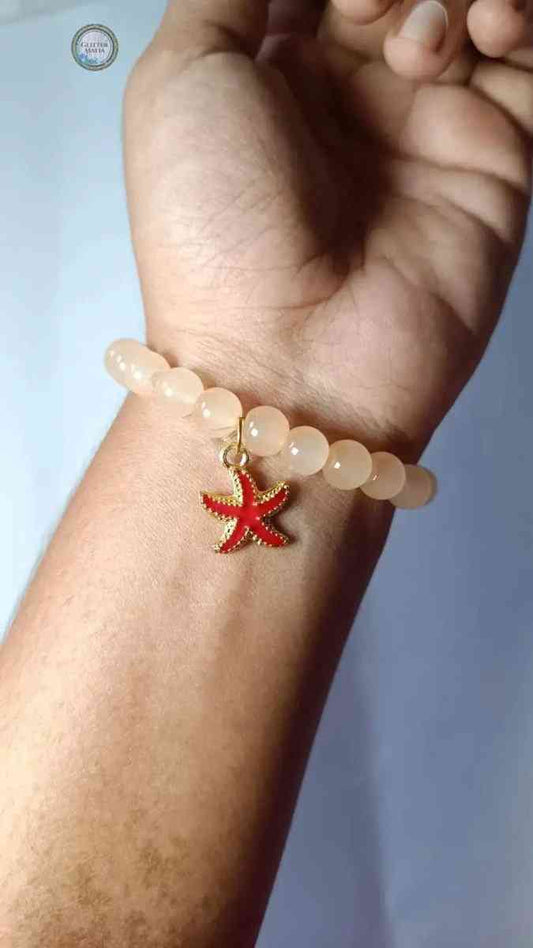 Glitter Mafia star fish bracelet with peach beads and red star fish charm on wrist