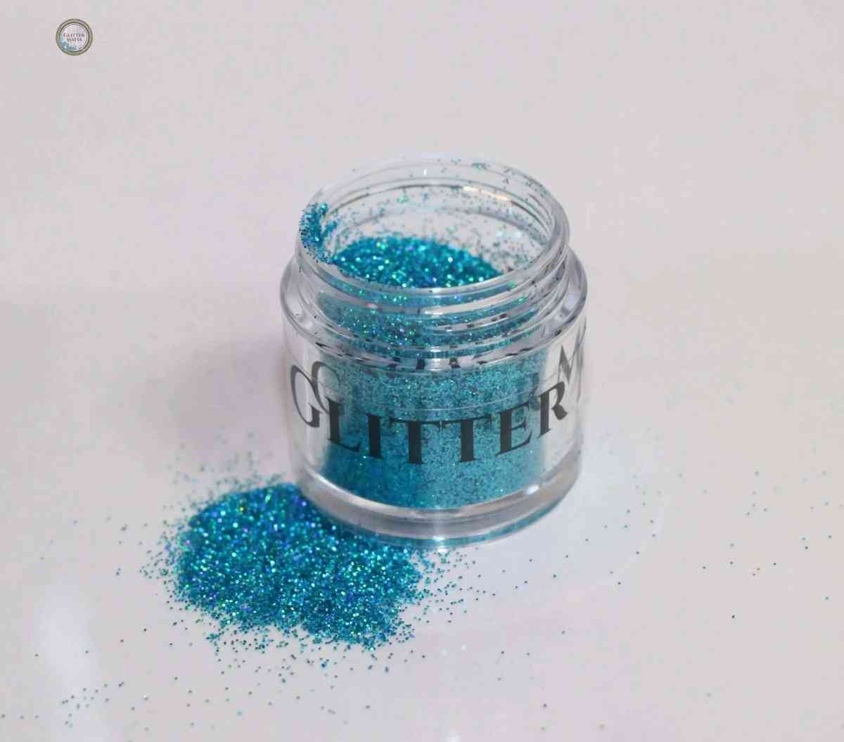 Glitter Mafia Blaze Holographic Loose Glitter in azure blue spilled beside small clear jar