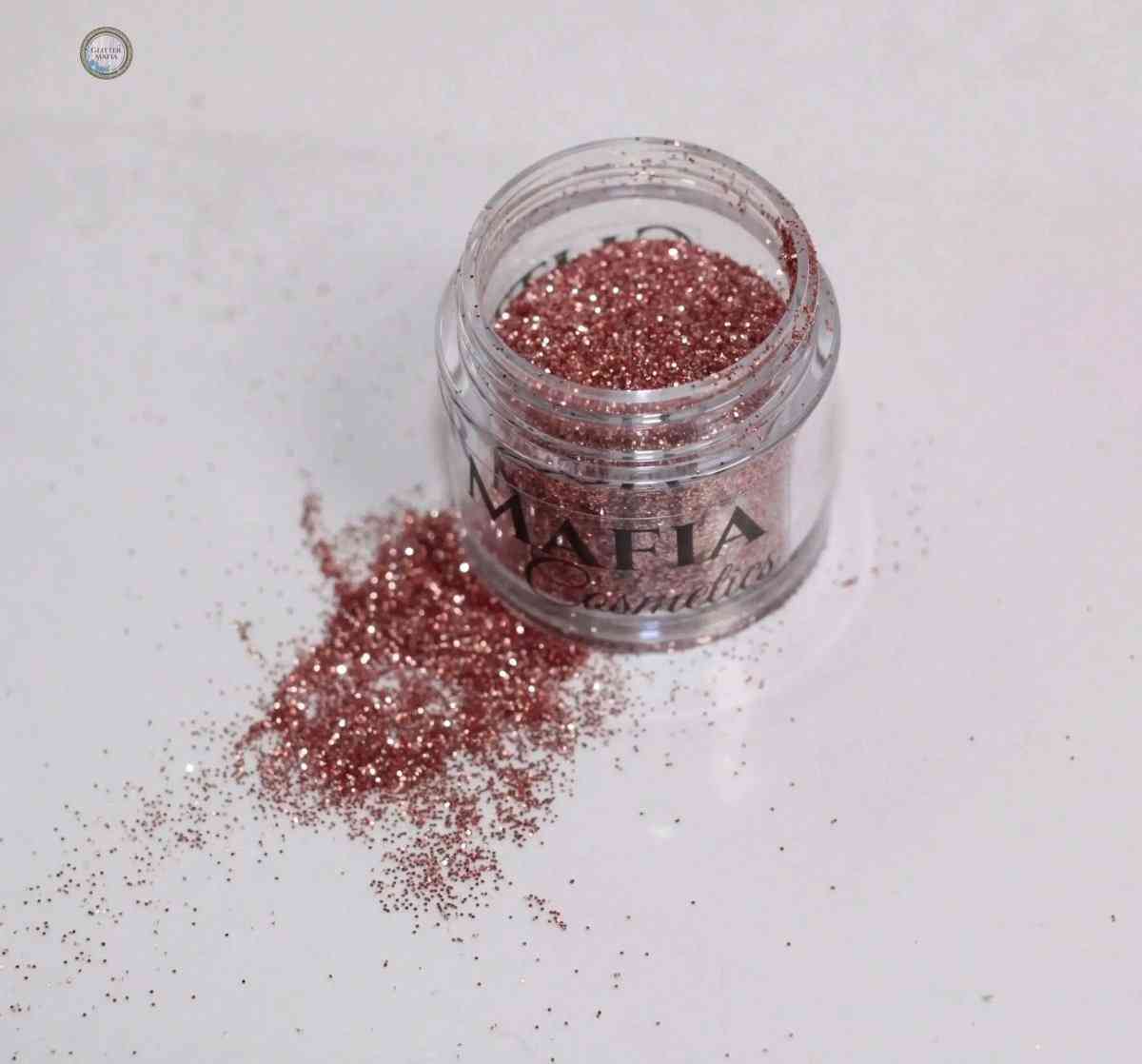 Glitter Mafia Charlotte Loose Glitter in a clear jar with rose gold shimmer spilled on white surface