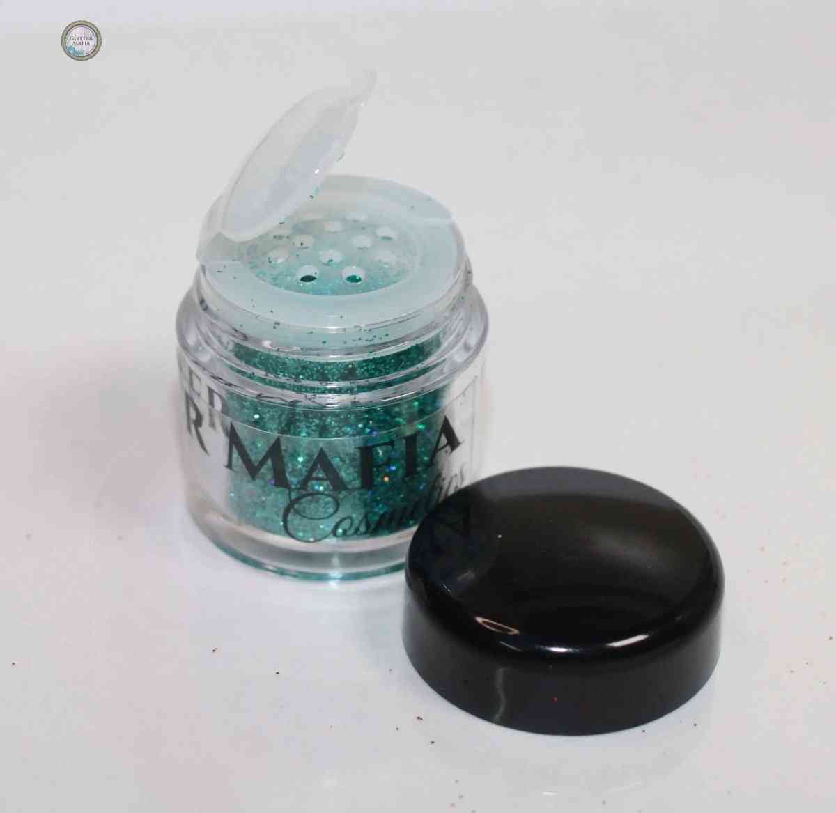 Glitter Mafia container of teal blue Flaunt Loose Glitter with black lid beside it