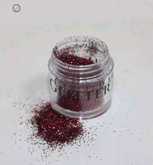 Glitter Mafia 24k gold dazzling loose glitter in an open jar with spilled glitter on white surface