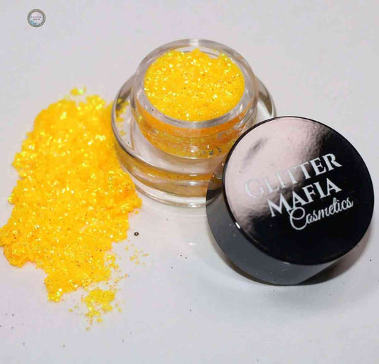 Mango Punch Pressed Glitter by Glitter Mafia in a small jar with bright yellow sparkle spilled beside it