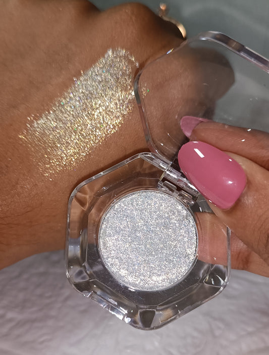 Glitter Mafia pressed glitter pot held by hand with pink nails and wrist swatch Moonlit Frost- Icy Golden with etheral Glow.