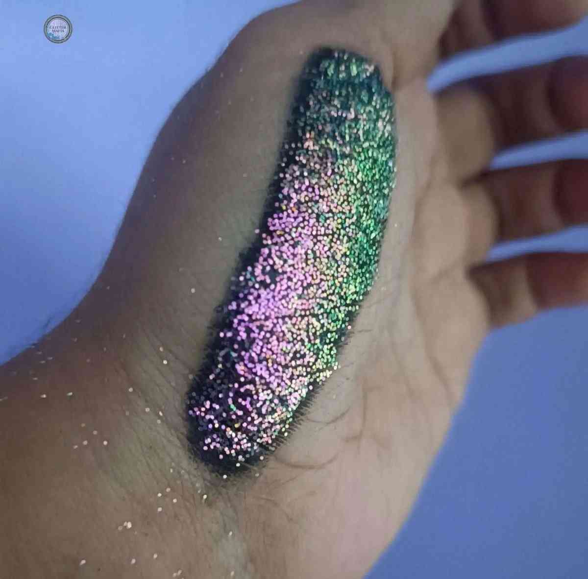 Swatch of Stella Chrome Glitter by Glitter Mafia showing iridescent pink and green glitter on skin